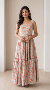 Woman wearing a Vasundhara Fashions beige floral print sleeveless maxi frock with a tiered skirt design.