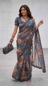 Vasundhara Fashions black floral organza saree with a matching blouse, clutch, and intricate lace border detail.