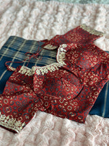 Vasundhara Fashions blue tissue saree paired with a maroon patterned blouse featuring intricate gold embroidery