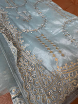 Vasundhara Fashions blue tissue saree featuring intricate gold embroidery and sparkling stone work detailing.