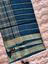 Vasundhara Fashions blue tissue saree with gold zari stripes and intricate border, featuring maroon tassel details.