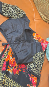 Vasundhara Fashions black chiffon saree with vibrant floral print, gold sequin border, and embellished blouse.