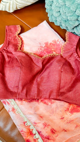 Vasundhara Fashions peach floral organza saree with a matching dark pink sleeveless blouse featuring gold embroidery.
