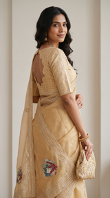 Vasundhara Fashions gold Kora embroidery saree with a scalloped back blouse and floral threadwork details.