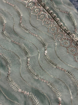 Vasundhara Fashions green organza saree featuring intricate silver sequin embroidery and wavy threadwork patterns.