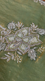 Vasundhara Fashions green organza saree featuring intricate floral embroidery with pearl, sequin, and silver beadwork.