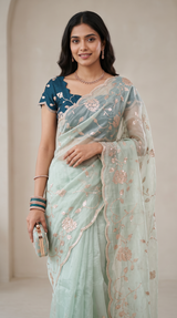 Vasundhara Fashions green soft organza saree with delicate floral embroidery and a matching teal scalloped blouse