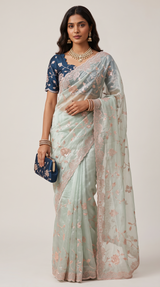 Vasundhara Fashions mint green organza saree with intricate floral embroidery and a matching navy blue blouse