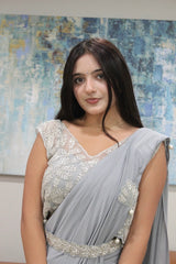 Woman wearing a Vasundhara Fashions grey drape saree with intricate silver embroidery and pearl embellishments