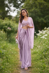 Vasundhara Fashions lavender croptop cape set with embroidered bodice and draped skirt worn by a woman in a garden.