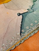 Vasundhara Fashions organza saree featuring a watercolor print and a diamond-patterned border with sparkling stones.