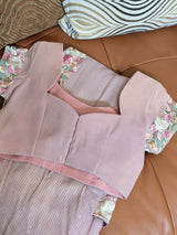 Vasundhara Fashions pink chiffon saree blouse with floral embroidery and sequin details on a leather sofa