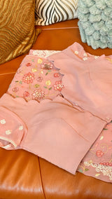 Vasundhara Fashions pink Chikankari saree with floral embroidery and a matching stitched scalloped-edge blouse.