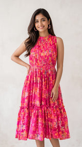 Woman wearing a Vasundhara Fashions pink floral pleated party frock with a high neckline and ruffled hem