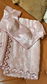 Vasundhara Fashions pink organza saree with sequin embroidery and matching satin blouse on a leather surface