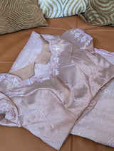 Vasundhara Fashions light pink and purple organza saree featuring intricate sequin embroidery on a leather sofa.