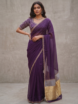 A woman wearing a deep purple Vasundhara Fashions Kora embroidery saree with intricate gold border detailing.