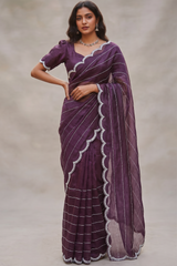 Model wearing a Vasundhara Fashions purple organza saree with silver horizontal lines and a beaded scalloped border.