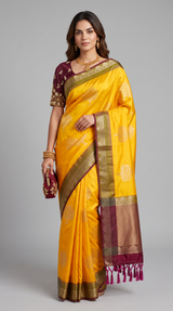 Model wearing a yellow Vasundhara Fashions Uppada Pattu silk saree with a maroon embroidered blouse and gold jewelry.